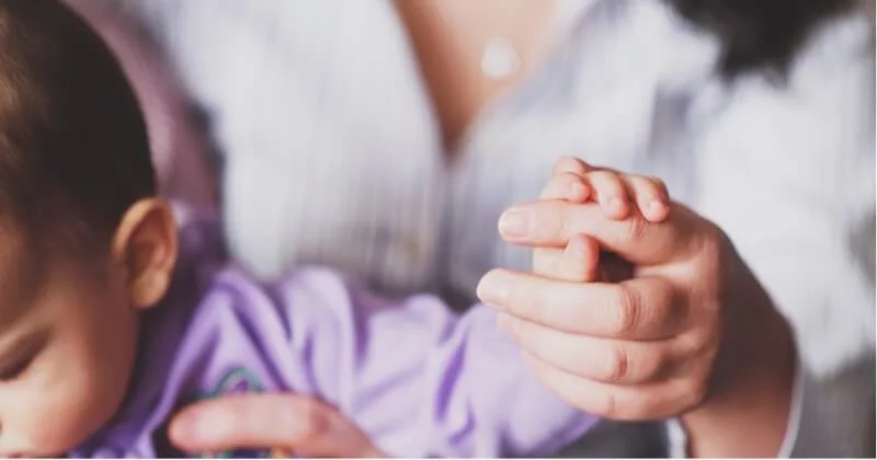 Baby und eine hilfreiche Erwachsenenhand