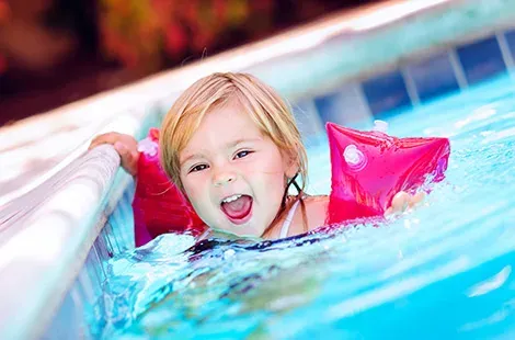 Baby- und Familienurlaub - Mädchen im Pool mit Schmwimmflügerl