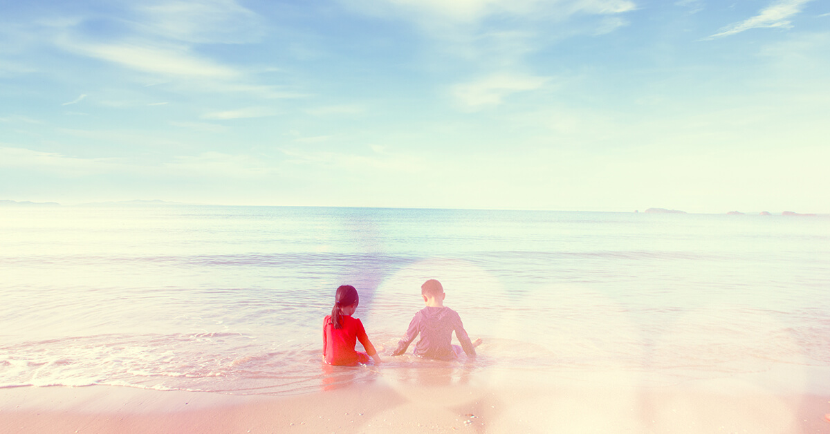 Zwei Kinder sitzen am Strand in einem träumerischen Bild